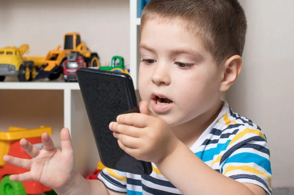 little boy 3 4 years old looks into the phone screen scaled e1656260386338 1